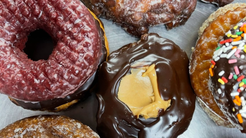 A close-up shot of a variety of freshly made donuts, including one filled with peanut butter.