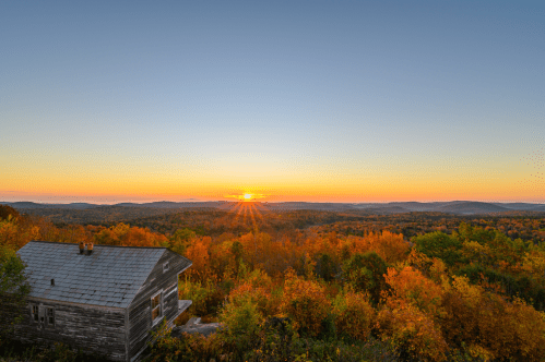 Stunning sunrise disappears behind mountain range as seen from Hogback Mountain in VT.