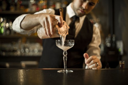 Bartender pouring a cocktail into a cocktail glass