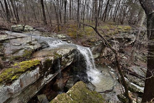 A waterfall runs down into a stream.