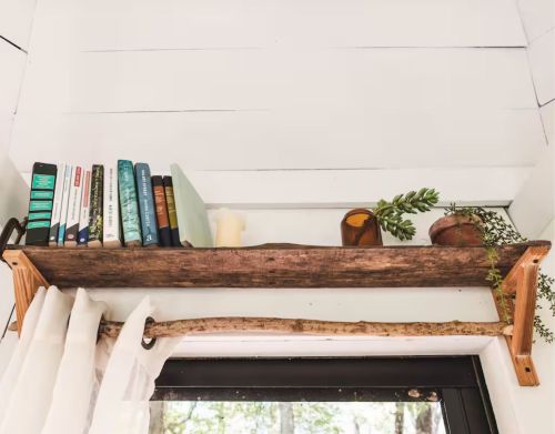 A wooden bookshelf above a doorframe against a white wall.