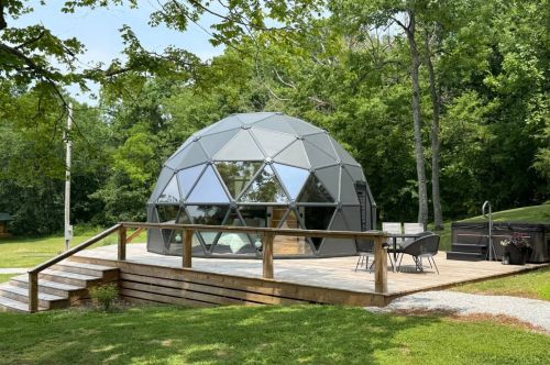 A bed with a white comforter in the loft of a glamping dome.