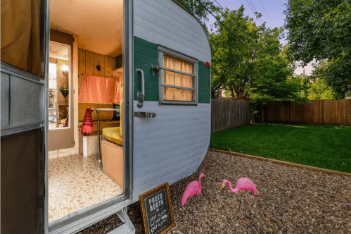 A pair of pink flamingos are located near the entrance of a 1970s travel trailer