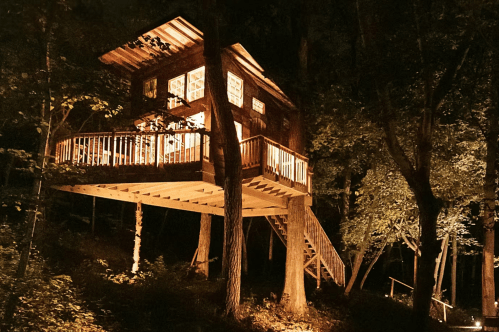 A treehouse in the woods is lit up after night
