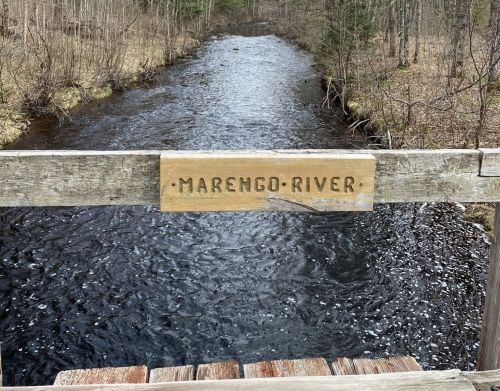 A wooden bridge with a sign over a river.
