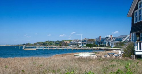 A clear blue sky filled with fluffy white clouds over a dock on the water in Orient, New York.