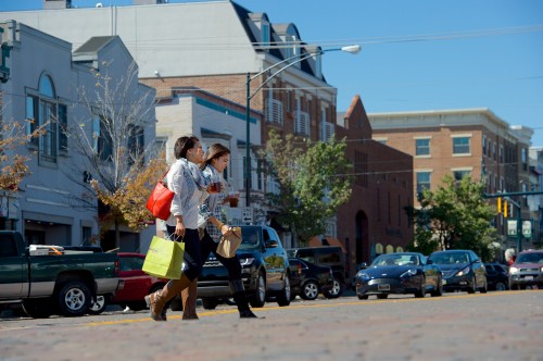 Two women crossing a street with shopping bags