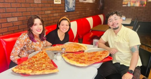 A group of customers and their giant pizzas at Richie B's