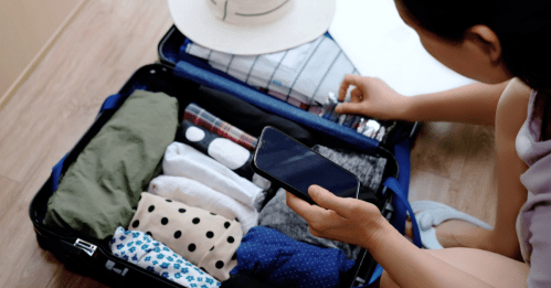 Person packing suitcase with rolled clothes