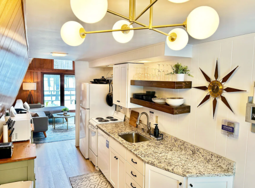 The kitchen area in the Beechwood Cottage with a pointed star clock on the wall and a gold light fixture in the foreground.