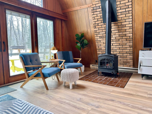 Sitting area with blue chairs and a vintage black gas fireplace in the Beechwood Cottage.