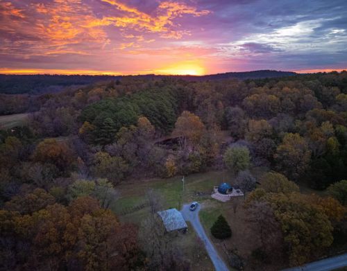 A birds-eye view of a glamping dome set against a forest at sunset.