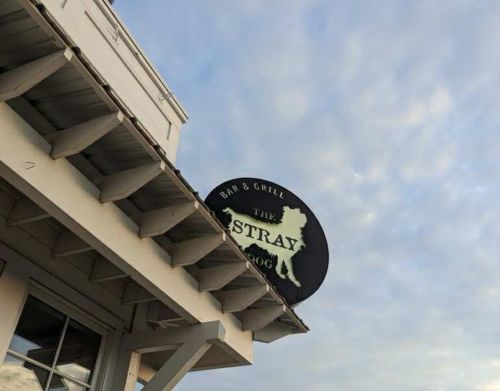 A sign for the Stray Dog Bar & Grill on top of a white building.
