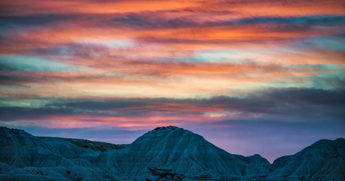 Vibrant orange and purple sunrise over the rugged, lunar-like badlands of Toadstool Geologic Park in Nebraska.
