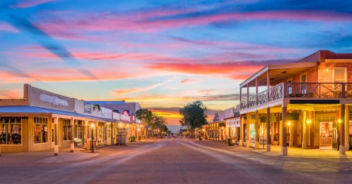 Looking down the street of Tombstone, Arizona, as a fiery sunset is overhead.