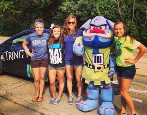 A group of women standing next to a college mascot of a blue troll.