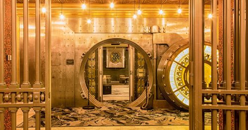 Bars with open doors to a bright room with a bank vault