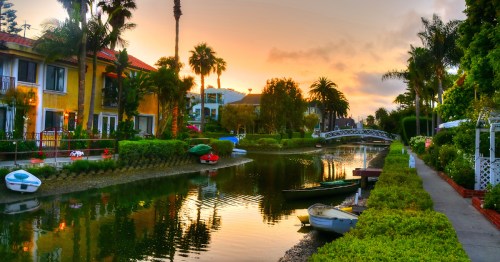 Boats of all colors and sizes line the historic canals in Venice, California, at sunset.