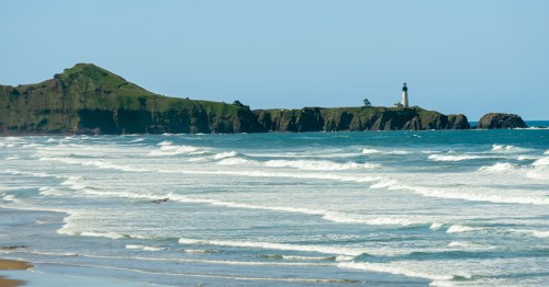 a lighthouse seen in the distance from the sand at beverly beach state park in oregon