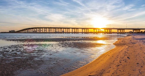 Sunset views over a pier spanning across the calm waters at Biloxi Beach in Mississippi.
