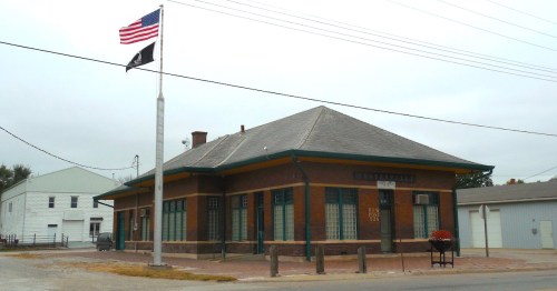 Flags wave over the historic Centerville, Iowa, train depot on a cloudy day.