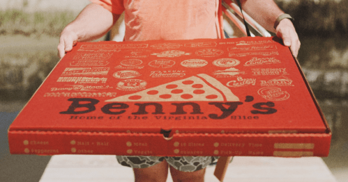 A person holds a giant red Benny's pizza box.