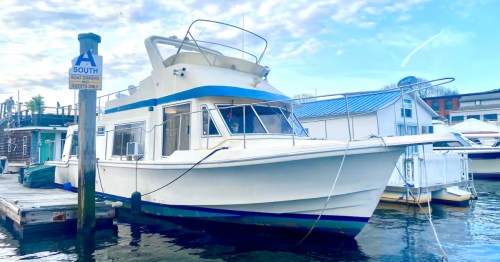 The exterior of the Lola & Jiji Houseboat Hotel Airbnb property in Providence, Rhode Island. The boat is docked at a pier.