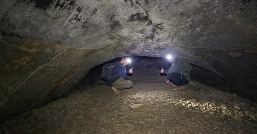 two men with headlamps inside the lava river tube in flagstaff arizona