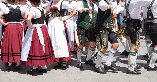 Women in dirndls and men in lederhosen dance at Oktoberfest