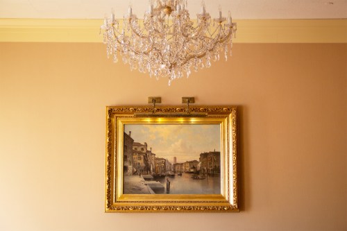 Painting hung on a wall under a chandelier