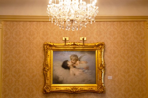Painting of two angelic figures under a chandelier