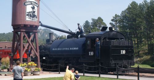 A black 1880s steam train and water tank.
