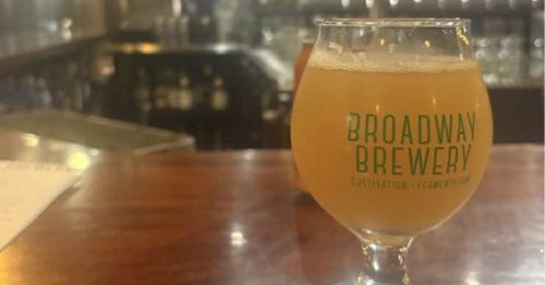 A hazy beer in a glass on a bar.