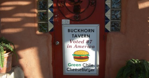 Sign outside restaurant that reads "Buckhorn Tavern, Voted #7 in America, Green Chile Cheeseburger"