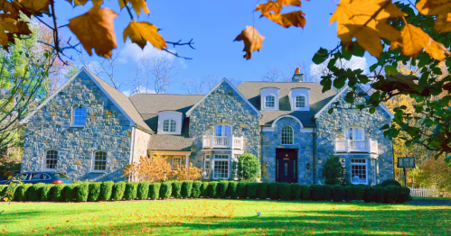 A grand stone castle Airbnb in Connecticut on a sunny day, with fall foliage accenting its sprawling front lawn.