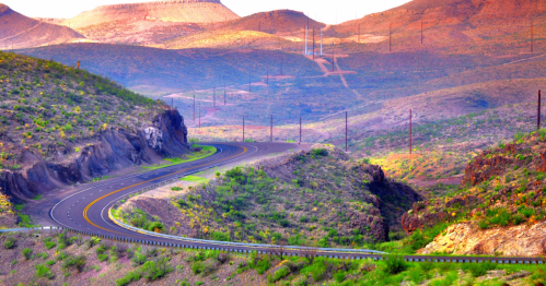 Scenic desert highway winding through the West Texas mountains at golden hour.