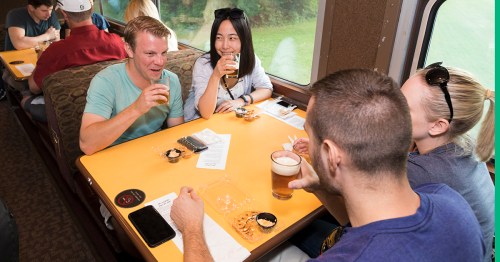four people seated at a table on a train