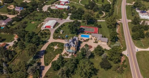 An aerial view of a Victorian-era castle and its property with a pool and pickleball court.