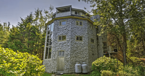 The stone castle exterior of the Dragonwood Castle AIrbnb property in Prospect Harbor, Maine.