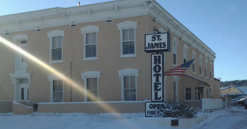 Exterior of the St. James Hotel and Saloon in Cimarron, New Mexico, on a sunny, snowy day.