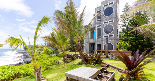 A modern building surrounded by green lawn looks out on the Pacific Ocean.