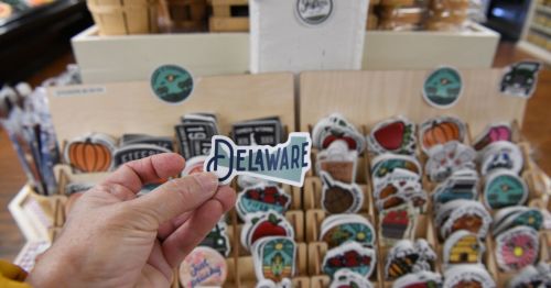 A hand holding a sticker that says "Delaware"