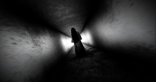 A black and white photo of a ghostly figure walking through a tunnel.