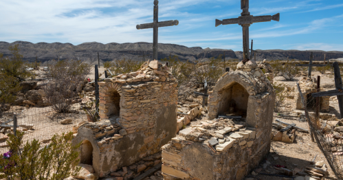 Crumbling stone graves with wooden crosses in the old Terlingua cemetery.