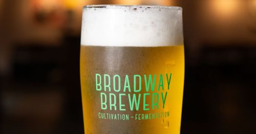 A close-up of a full beer glass that says “Broadway Brewery” on it.