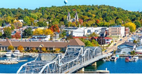 A bridge crossing a river with a town and a hill behind it.