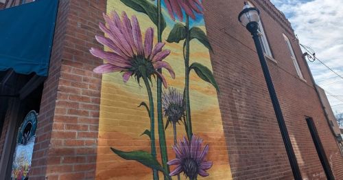 A mural depicting flowers on the exterior of a building made of brick.