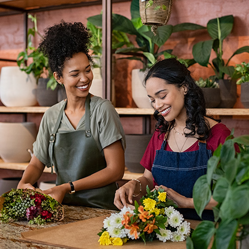 Two Latina small business owners work at a flower shop.