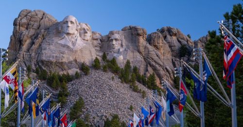 A view of Mount Rushmore National Memorial with state flags underneath.
