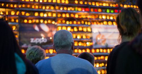 People looking up at a wall of lit jack-o-lanterns.